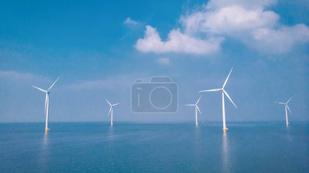 Foto de Parque de molinos de viento en alta mar con nubes y un cielo azul, parque de molinos de viento en la vista aérea del océano de la turbina eólica Flevoland Holanda Ijsselmeer. Energía verde - Imagen libre de derechos