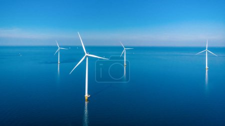 Foto de Parque de molinos de viento en alta mar con nubes y un cielo azul, parque de molinos de viento en la vista aérea del océano de la turbina eólica Flevoland Holanda Ijsselmeer. Energía verde - Imagen libre de derechos
