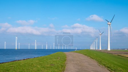 Foto de Parque de molinos de viento en alta mar con nubes y un cielo azul, parque de molinos de viento en la vista aérea del océano con turbina eólica Flevoland Países Bajos Ijsselmeer. - Imagen libre de derechos