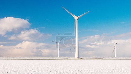 Foto de Parque de molinos de viento con nieve durante el invierno y un cielo azul, parque de molinos de viento en la vista aérea del océano con turbina eólica Flevoland Países Bajos Ijsselmeer. Energía verde - Imagen libre de derechos
