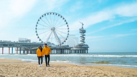 Téléchargez les photos : Couple sur la plage de Scheveningen Pays-Bas au printemps, La Grande Roue à La jetée à Scheveningen aux Pays-Bas - en image libre de droit