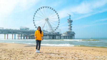 Photo for Women on the beach of Scheveningen Netherlands during Spring, The Ferris Wheel at The Pier at Scheveningen in the Netherlands - Royalty Free Image