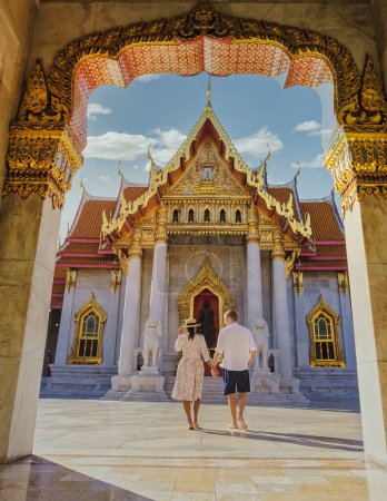 Photo for Wat Benchamabophit temple in Bangkok Thailand, The Marble temple in Bangkok. Asian woman with a hat and European men visiting a temple, a couple on a city trip in Bangkok - Royalty Free Image