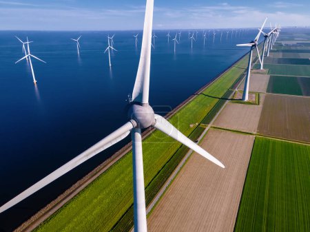 Photo for Windmill Park with a blue sky and green agricultural field, and windmill turbines park in the ocean. Netherlands Europe the biggest wind park in the Netherlands - Royalty Free Image
