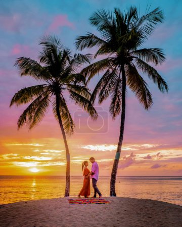 Foto de Santa Lucía Caribbean Island, una pareja de vacaciones de lujo en la isla tropical de Santa Lucía observando la puesta de sol en la playa con cocoteros y un cielo anaranjado - Imagen libre de derechos
