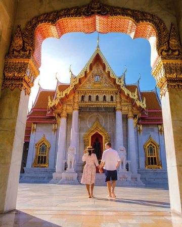 Photo for A couple of men and women visit Wat Benchamabophit temple in Bangkok Thailand, The Marble temple in Bangkok. Asian woman with a hat and European men visiting a temple in Bangkok - Royalty Free Image
