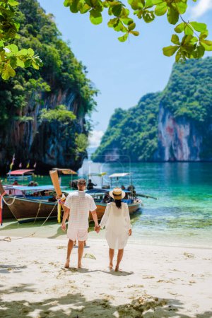 Téléchargez les photos : Koh Lao Lading près de Koh Hong Krabi Thaïlande, belle plage avec des bateaux à queue longue, un couple d'hommes européens, et une femme asiatique sur la plage. Couple en excursion en bateau - en image libre de droit