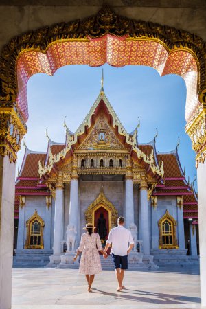 Photo for Asian woman with a hat and European men visiting a temple, a couple on a city trip in Bangkok Thailand, Wat Benchamabophit temple in Bangkok Thailand, The Marble temple in Bangkok. - Royalty Free Image