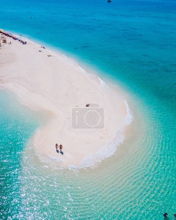 Photo for Men and women walking on a sandbar in the ocean of Koh Lipe Southern Thailand during vacation. a couple at a sandbank in a turqouse colored ocean during a beautiful summer day - Royalty Free Image