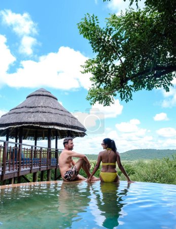 Paar Männer und Frauen am Pool auf einer Luxus-Safari, Südafrika, einer Luxus-Safari-Lodge im Busch eines Wildreservats