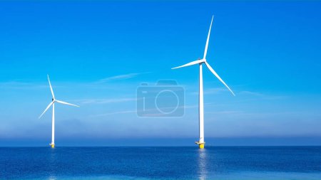 Photo for Windmill park with clouds and a blue sky, windmill park in the ocean aerial view with wind turbine Flevoland Netherlands Ijsselmeer. Green energy production in the Netherlands - Royalty Free Image