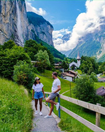 Foto de Hombres y mujeres que visitan el valle de Lauterbrunnen con una hermosa cascada y los Alpes suizos en el fondo, Berner Oberland, Suiza, Europa durante el verano - Imagen libre de derechos