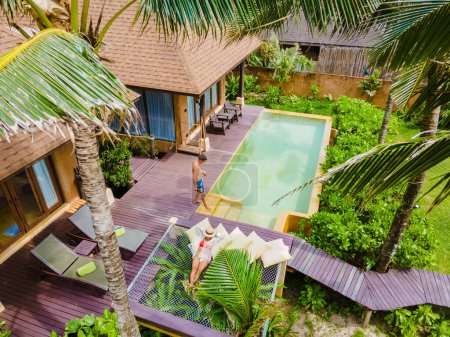 Téléchargez les photos : Maison moderne avec piscine, villa moderne avec piscine sur la plage, villa de luxe en Thaïlande, un couple d'hommes et de femmes en vacances de luxe en Thaïlande dans un complexe 5 étoiles relaxant dans la piscine - en image libre de droit