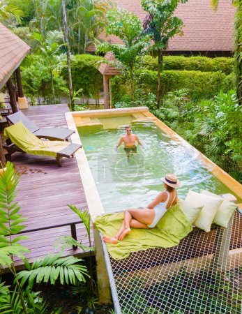 Téléchargez les photos : Maison avec piscine, villa moderne avec piscine, villa de luxe en Thaïlande, un couple d'hommes et de femmes en vacances de luxe en Thaïlande dans un complexe 5 étoiles relaxant dans la piscine pendant les vacances - en image libre de droit