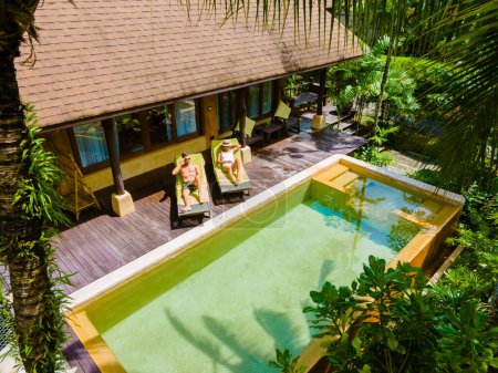 Téléchargez les photos : Maison avec piscine, villa moderne avec piscine, villa de luxe en Thaïlande, un couple d'hommes et de femmes en vacances de luxe en Thaïlande dans un complexe 5 étoiles relaxant dans la piscine pendant les vacances - en image libre de droit