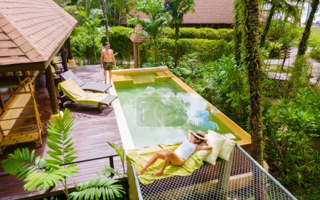 Téléchargez les photos : Un couple d'hommes et de femmes en vacances de luxe en Thaïlande dans un complexe 5 étoiles relaxant dans la piscine maison moderne avec piscine, villa piscine moderne à la plage, villa de luxe en Thaïlande - en image libre de droit