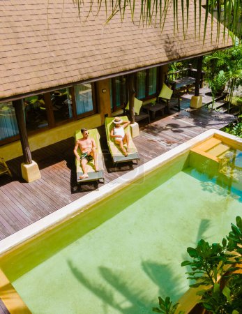 Téléchargez les photos : Maison moderne avec piscine, villa moderne avec piscine sur la plage, villa de luxe en Thaïlande, un couple d'hommes et de femmes en vacances de luxe en Thaïlande dans un complexe 5 étoiles relaxant dans la piscine - en image libre de droit