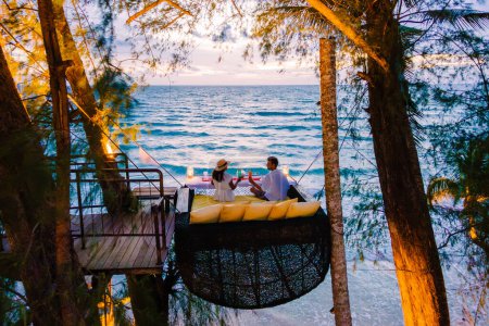 Foto de Cena romántica en la playa de Koh Kood Tailandia, un par de hombres y mujeres cenando en la playa en lo alto del árbol en un nido de aves en Tailandia al atardecer - Imagen libre de derechos