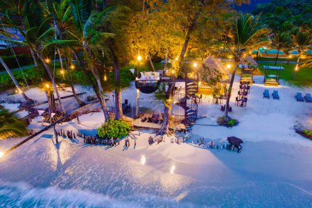 Téléchargez les photos : Dîner romantique sur la plage à Koh Kood Thaïlande, un couple d'hommes et de femmes dînant sur la plage haut dans l'arbre à un nid d'oiseaux en Thaïlande pendant le coucher du soleil à Ko Kut Trat pendant des vacances de luxe - en image libre de droit