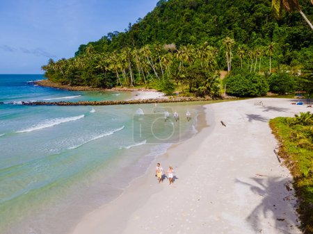 Téléchargez les photos : Ao Phrao Beach Koh Kood Island Thaïlande Trat, plage tropicale avec palmiers et une turque couleur océan par une journée ensoleillée, couple marchant sur la plage de Ko Kut Island - en image libre de droit