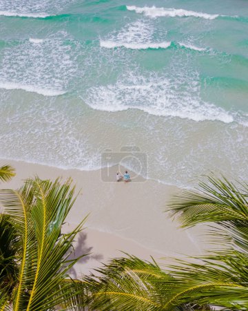 Téléchargez les photos : Un couple d'hommes et de femmes marchant à White Beach Koh Kood Island Thaïlande Trat, drone vue aérienne d'une plage tropicale avec des palmiers suspendus et une turque couleur océan par une journée ensoleillée, Ko Kut Island - en image libre de droit