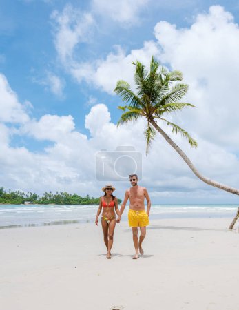 Téléchargez les photos : Secret BeachKoh Kood Island Thaïlande Trat, un couple d'hommes et de femmes marchant sur une plage tropicale avec des palmiers et une turque couleur océan par une journée ensoleillée pendant les vacances - en image libre de droit
