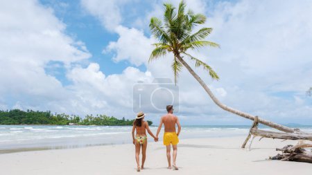 Photo for Secret BeachKoh Kood Island Thailand Trat, a diverse multiracial couple of men and women walking at a tropical beach with palm trees and a turqouse colored ocean on a sunny day during vacation - Royalty Free Image