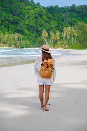 Foto de Mujer asiática con mochila caminando en la playa Koh Kood Island Thailand Trat, viajero caminando en la playa de la isla tropical Ko Kut Island con palmeras de coco en la playa, aviones no tripulados - Imagen libre de derechos