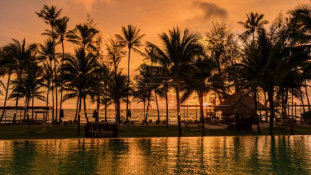 Téléchargez les photos : Coucher de soleil dans une piscine tropicale avec palmiers sur l'île de Koh Kood Thaïlande, piscine pendant le coucher de soleil sur la plage dans un hôtel de luxe - en image libre de droit