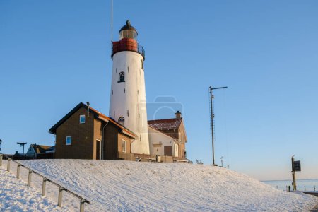 Téléchargez les photos : Phare d'Urk Pays-Bas en hiver avec neige aux Pays-Bas avec un ciel bleu - en image libre de droit