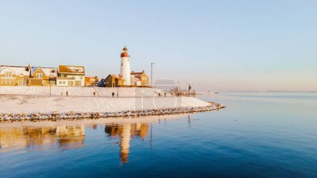 Photo for Lighthouse of Urk Netherlands during winter with snow in the Netherlands with reflections in the ocean - Royalty Free Image