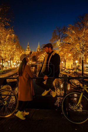 Téléchargez les photos : Amsterdam Pays-Bas pendant la saison d'hiver, un couple d'hommes et une femme visitent la ville d'Amsterdam avec pendant les vacances de Noël. voyage à Amsterdam entre hommes et femmes d "âge moyen - en image libre de droit