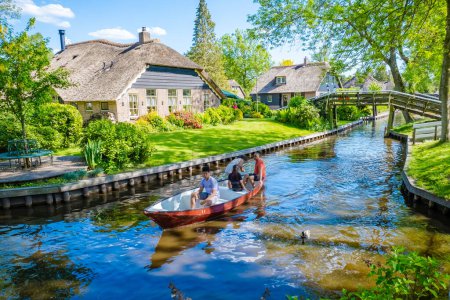 Téléchargez les photos : Giethoorn Pays-Bas 9 mai 2020, Les touristes en bateau visitent le célèbre village avec des canaux et des maisons de toit de chaume rustiques dans une zone agricole lors d'une chaude journée de printemps en Europe - en image libre de droit