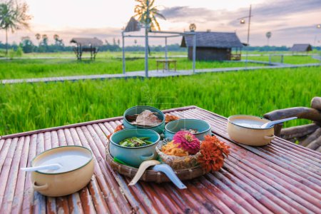 Photo for Thai breakfast with a green rice paddy field during sunrise, rice soup on a table in a green rice field - Royalty Free Image