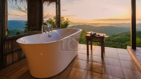 Téléchargez les photos : Baignoire donnant sur les montagnes de Chiang Rai Nord de la Thaïlande pendant les vacances. Salle de bains extérieure, baignoire au coucher du soleil - en image libre de droit