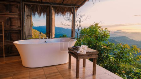 Photo for Bathtub looking out over the mountains of Chiang Rai Northern Thailand during vacation. Outdoor bathroom, bathtub during sunset - Royalty Free Image