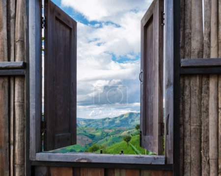 Téléchargez les photos : Une vue à travers une fenêtre en bois sur les montagnes verdoyantes des montagnes de Doi Chang de Chiang Rai Nord de la Thaïlande, vue sur la montagne naturelle sur Doi Chang, province de Chiang Rai, Thaïlande - en image libre de droit