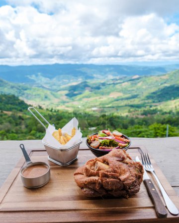 Foto de Nudillo de cerdo alemán con vistas a las montañas de Chiang Rai norte de Tailandia durante las vacaciones. Nudillo de cerdo alemán en un restaurante en las montañas - Imagen libre de derechos