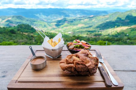 Téléchargez les photos : Jarret de porc allemand donnant sur les montagnes de Chiang Rai Nord de la Thaïlande pendant les vacances. Poignée de porc allemande dans un restaurant en montagne - en image libre de droit