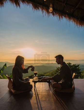 Photo for A couple of men and woman on vacation in Thailand waking up with drip coffee in the morning, with a look at the mountains of Doi Chang Chiang Rai Thailand - Royalty Free Image