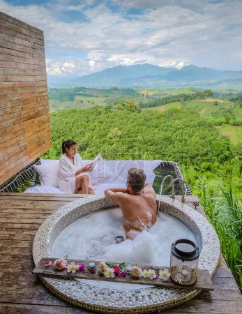 Téléchargez les photos : Un couple d'hommes et de femmes dans une baignoire donnant sur les montagnes du nord de la Thaïlande pendant les vacances. - en image libre de droit