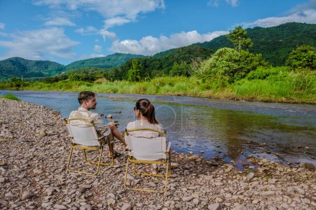 Téléchargez les photos : Un couple d'hommes et de femmes campant au bord de la rivière à Nan Sapan Thaïlande, hommes et femmes se détendre dans les montagnes du nord de la Thaïlande - en image libre de droit