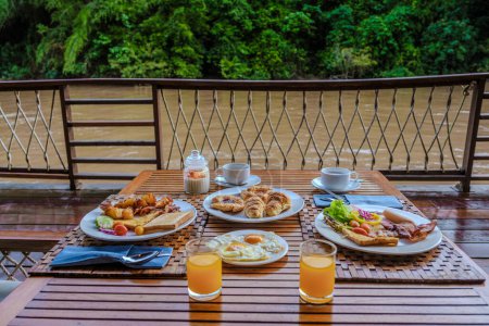 Téléchargez les photos : Table de petit déjeuner dans une maison de plage tropicale sur la rivière Kwai en Thaïlande.Maison de radeau flottant en bois dans la rivière Kwai Kanchanaburi, Thaïlande, petit déjeuner avec œufs pain et café - en image libre de droit