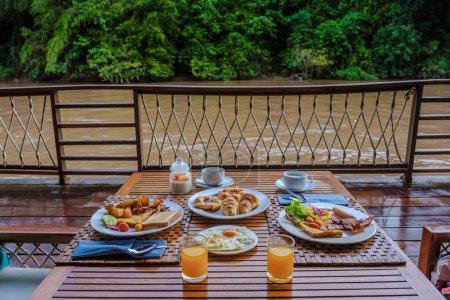 Téléchargez les photos : Table de petit déjeuner dans une maison de plage tropicale sur la rivière Kwai en Thaïlande.Maison de radeau flottant en bois dans la rivière Kwai Kanchanaburi, Thaïlande - en image libre de droit