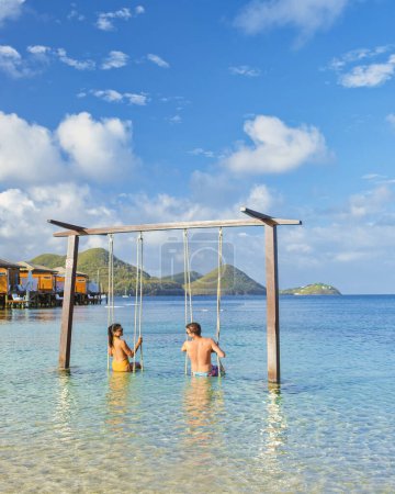 Photo for A Couple playing on a swing on the beach of the tropical Island Saint Lucia or St Lucia Caribbean, holiday vacation. men and women on a luxury vacation relaxing in the ocean on the beach of St Lucia - Royalty Free Image