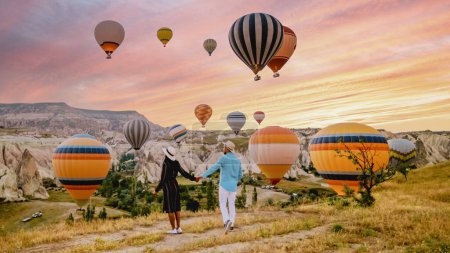 Photo for Cappadocia Turkey during sunrise, a mature couple of men and woman on vacation in the hills of Goreme Cappadocia Turkey, men and woman looking sunrise with hot air balloons in Cappadocia Turkey - Royalty Free Image