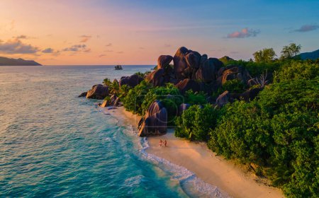 Photo for Anse Source dArgent beach, La Digue Island, Seychelles, drone view from above at a couple of men and woman walking at the beach during sunset at a luxury vacation in the Seychelles - Royalty Free Image