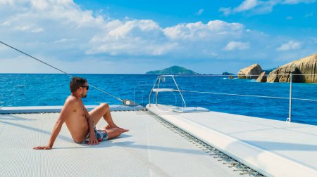 Téléchargez les photos : Young men on a trip with a Sailing boat at the Tropical Seychelles Islands. - en image libre de droit