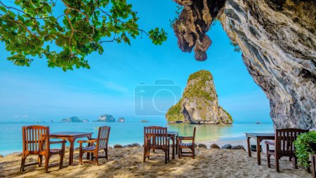 Photo for Restaurant table at Railay Beach Krabi Thailand, the tropical beach of Railay Krabi, idyllic Railay Beach in Thailand in the evening at sunset with a cloudy sky - Royalty Free Image