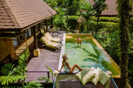 Téléchargez les photos : Maison moderne avec piscine, villa piscine moderne à la plage, villa de luxe en Thaïlande, un couple d'hommes et de femmes en vacances de luxe en lune de miel en Thaïlande - en image libre de droit